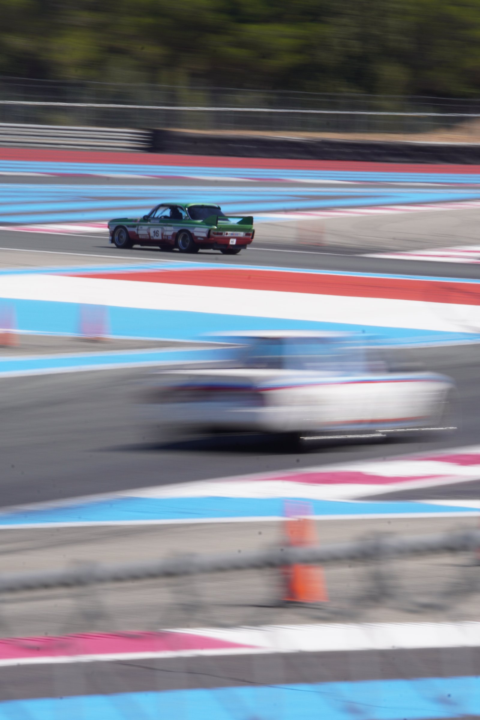 Voitures de course vintage sur piste, bandes bleu blanc rouge